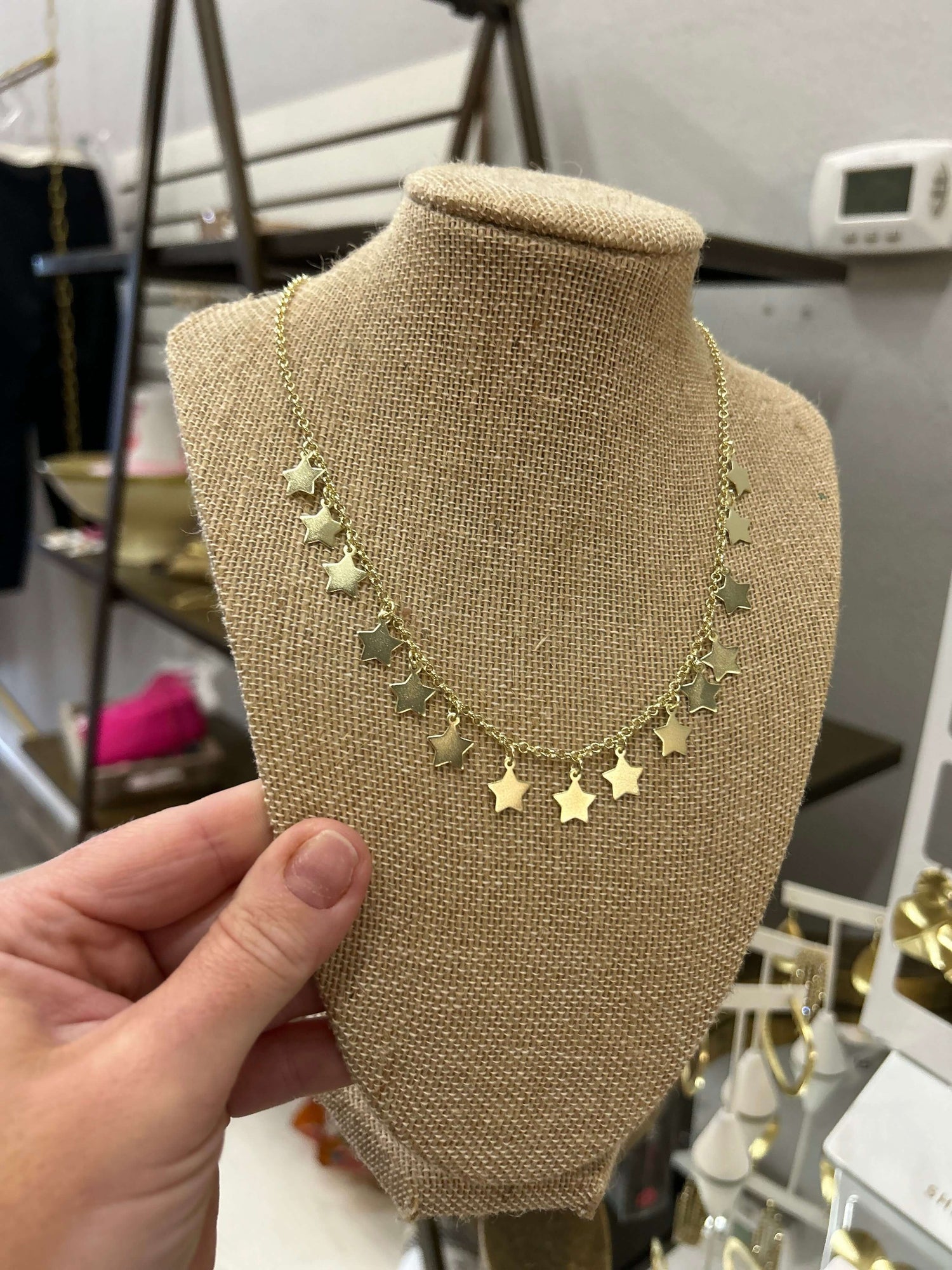 Gold star necklace displayed on a linen bust, showcasing a trendy and festive design.