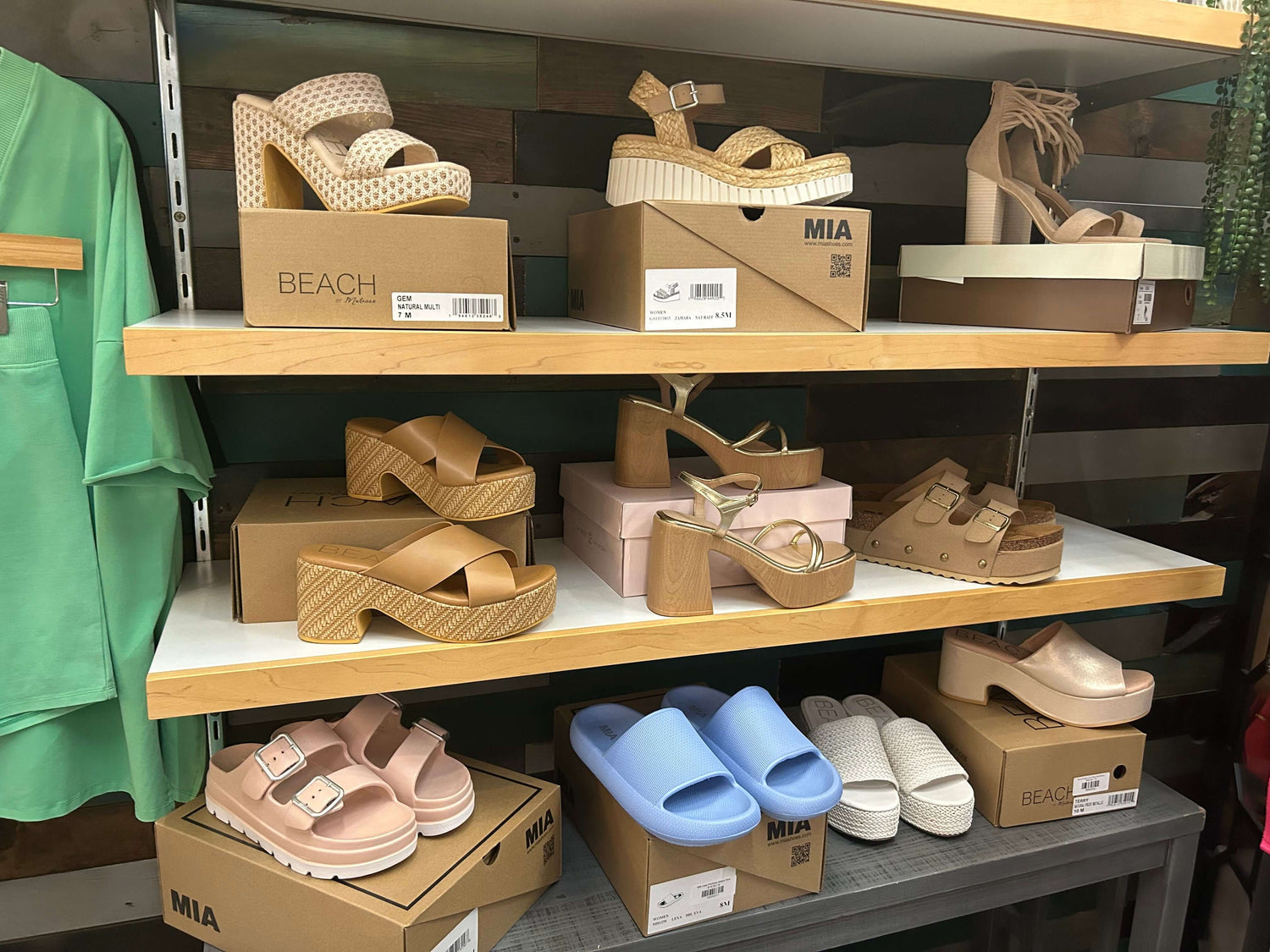 Stylish assortment of women's shoes including sandals, clogs, and slides displayed on wooden shelves.