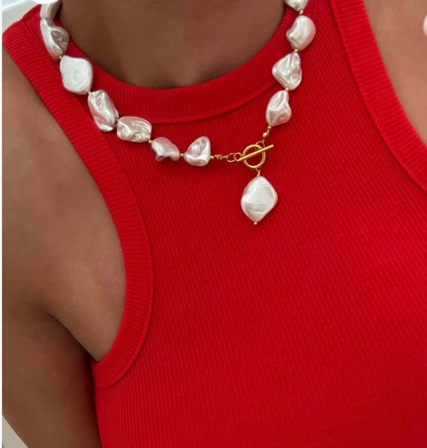 Chunky pearl necklace worn with a red top, ideal for summer and waterproof, perfect for any outfit.