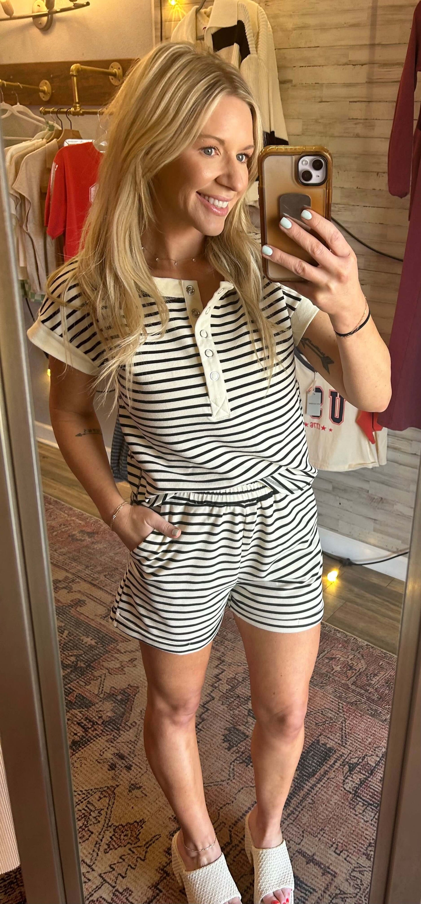 Model wearing cream 2pc striped Snap Henley set with elastic waist shorts and cap sleeves, smiling in a mirror.