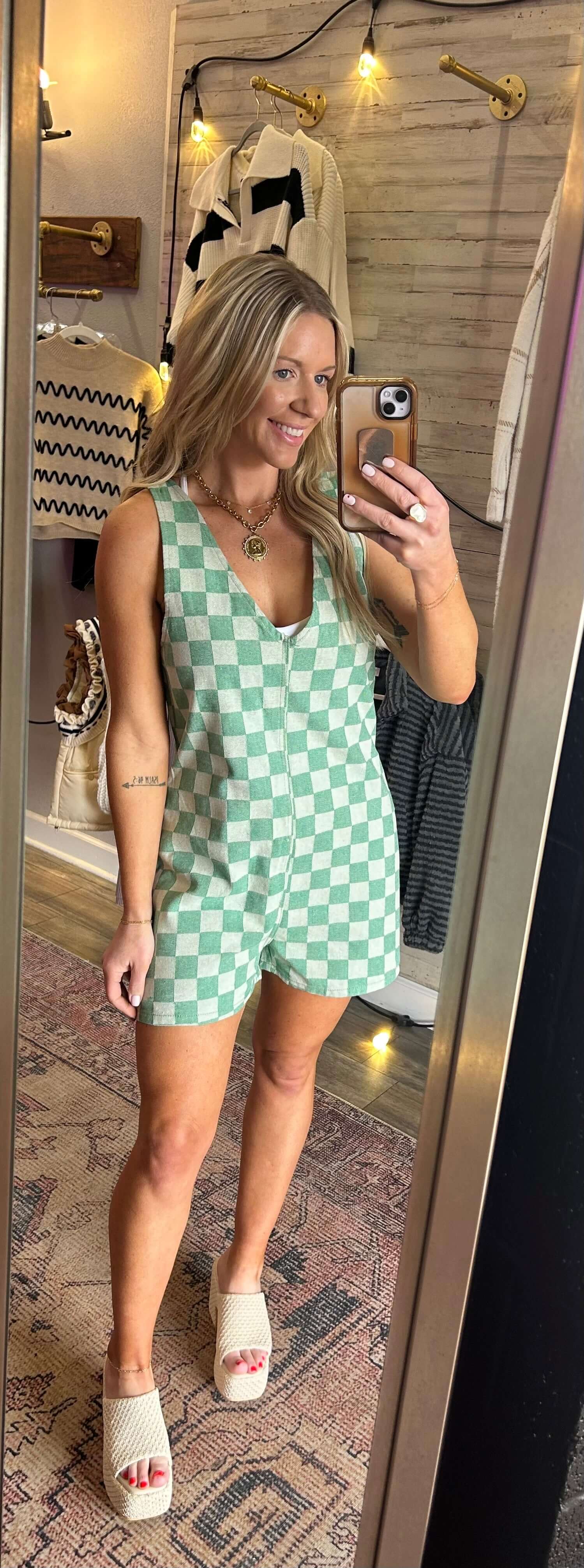 Model wearing a checkered evergreen romper with V neck, side zip, showcasing summer fashion style.