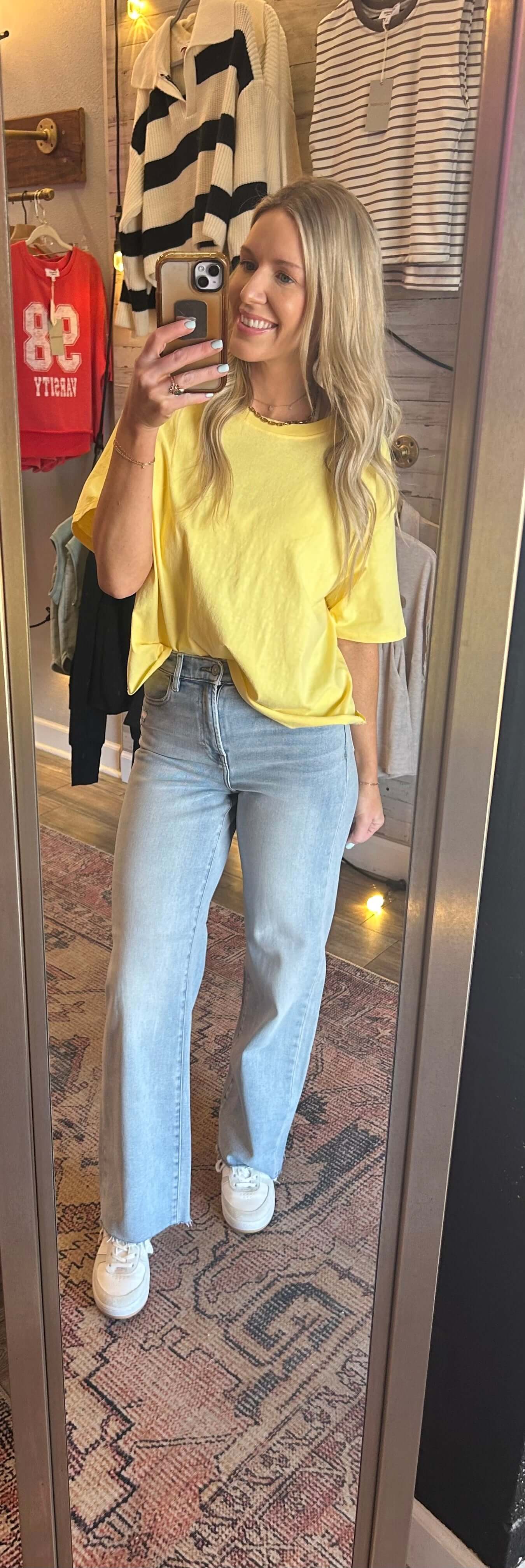 Woman in yellow tee and light wash highrise Dad jeans standing in front of a mirror, showcasing a casual spring outfit.