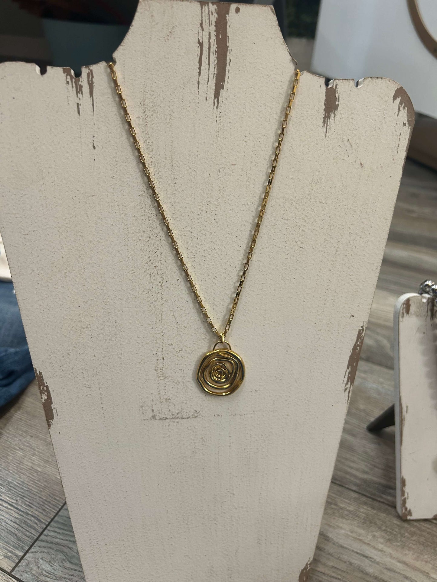 Gold swirly pendant necklace on display, part of the KristalizeJewelry 100% waterproof collection.
