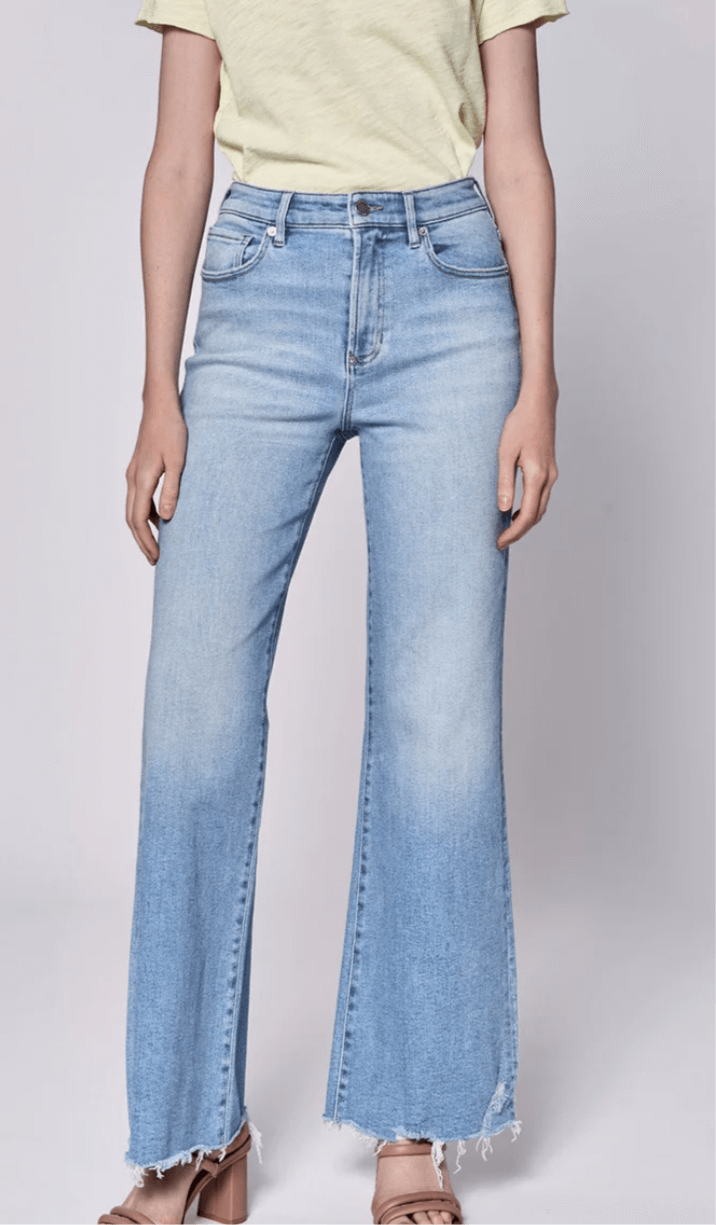 Model wearing high rise full inseam jeans with frayed hem, paired with a yellow top for a stylish look.