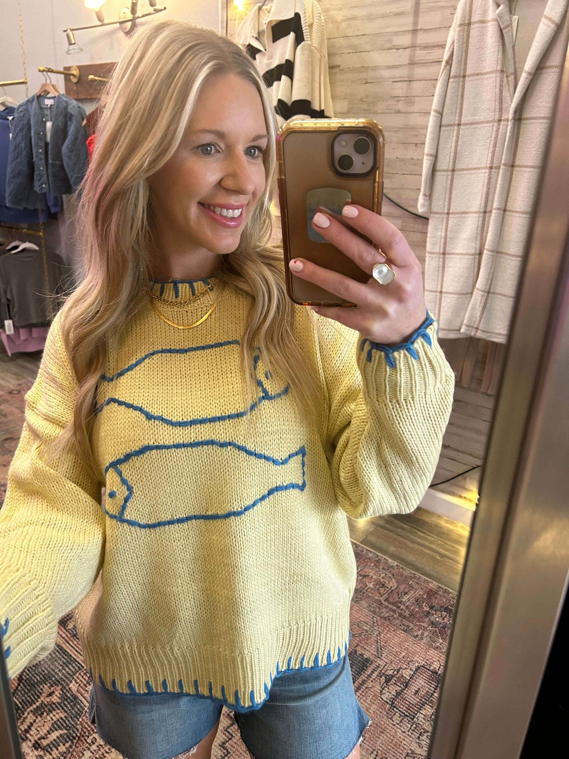 Smiling woman wearing a butter-colored crochet Fish summer sweater with blue stitching, perfect for spring and summer styling.