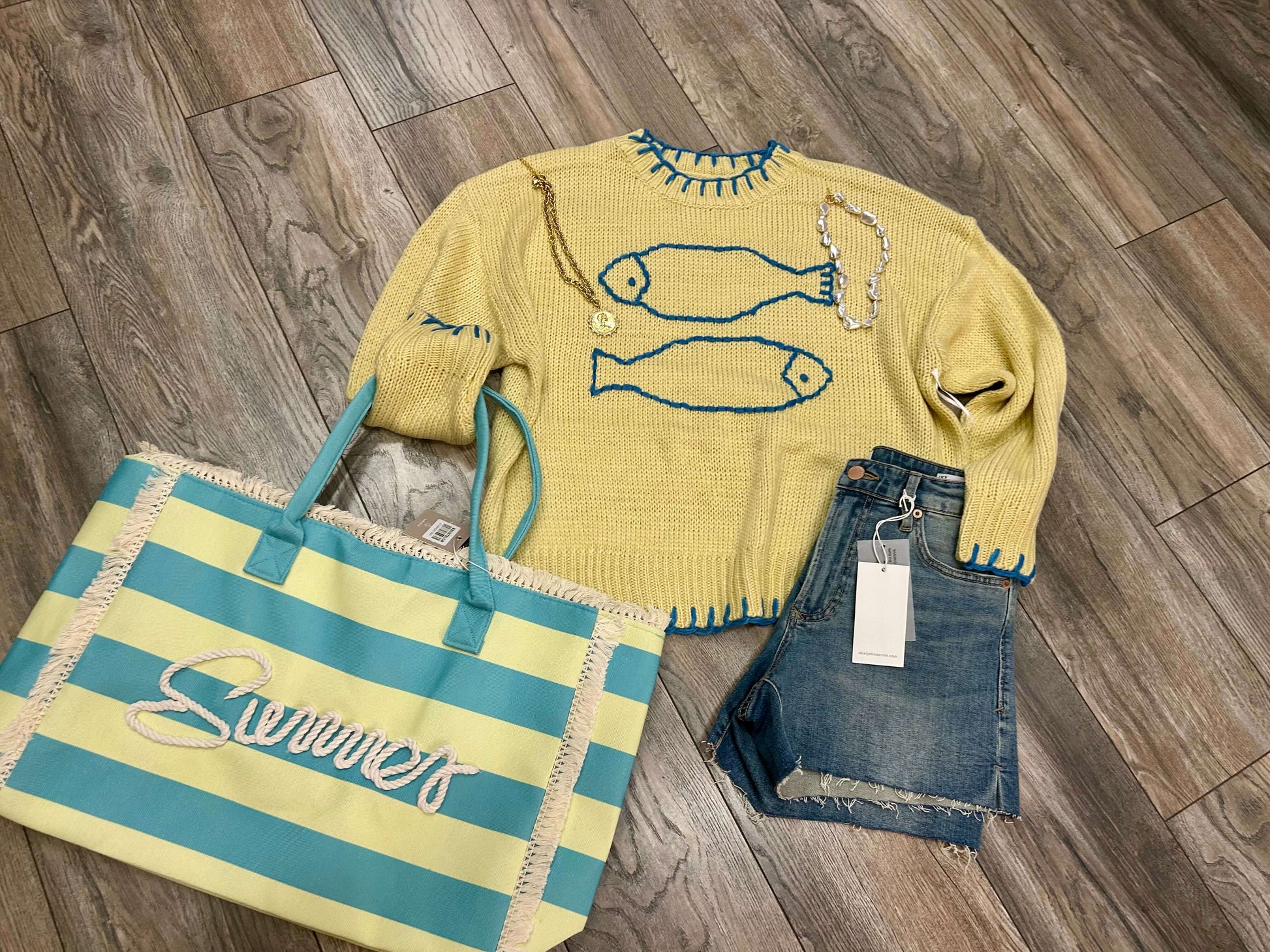 Crochet fish summer sweater in butter color, styled with blue stitching, alongside denim shorts and a striped tote bag.