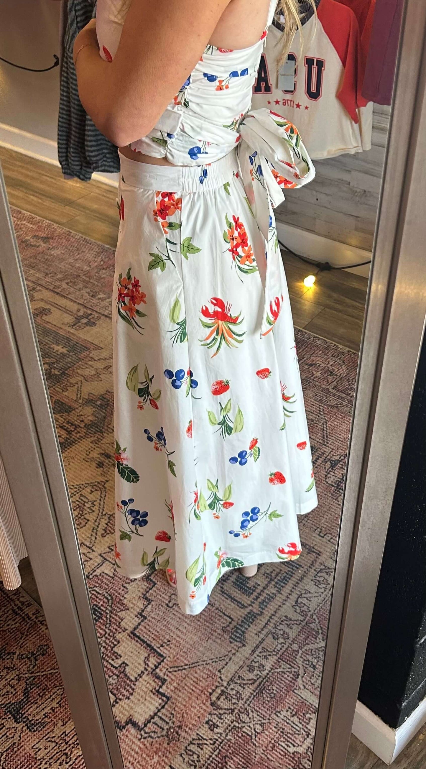 Lady wearing a floral 2pc skirt set with adjustable straps, featuring vibrant summer colors and an elastic waist skirt.