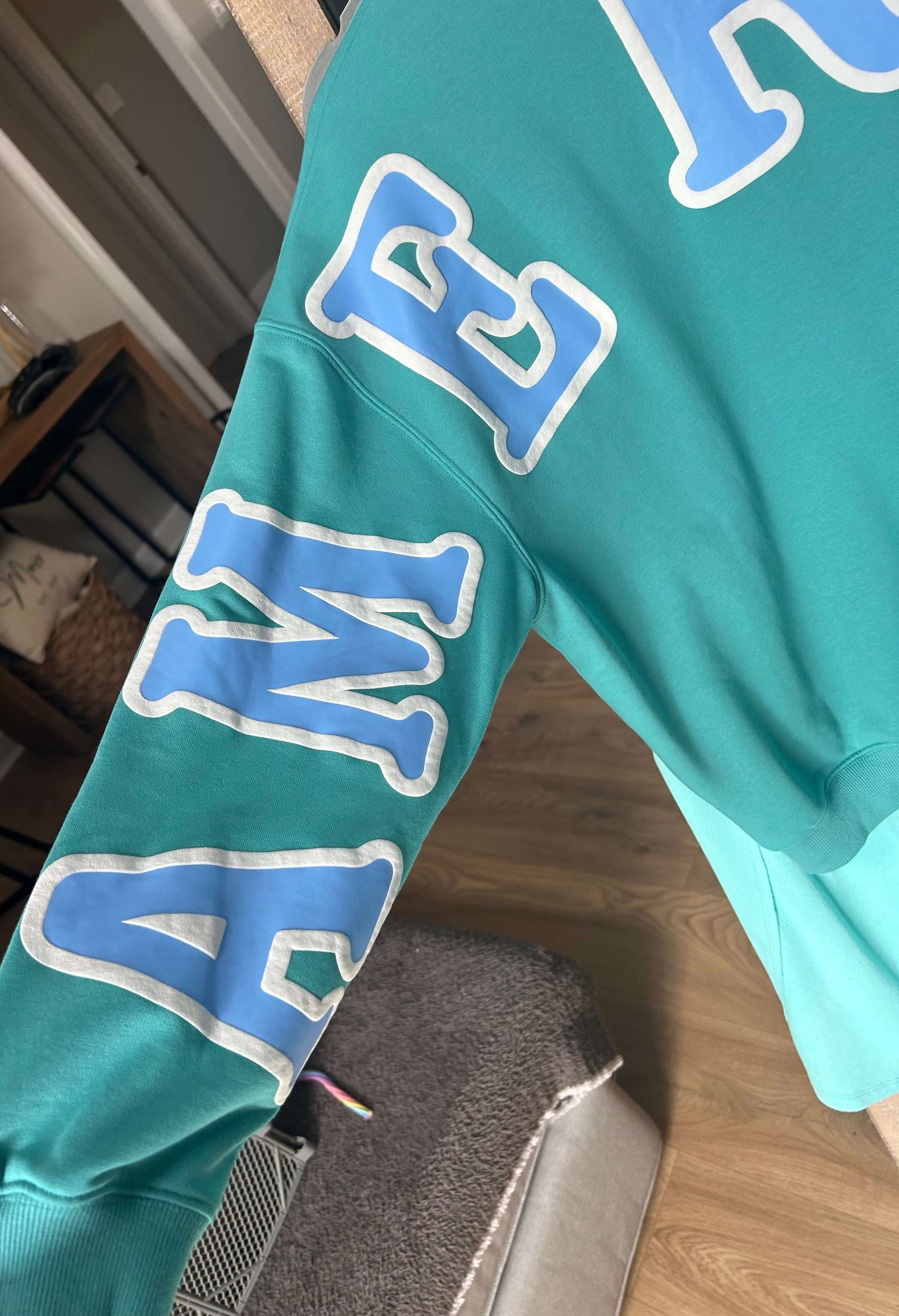 Emerald green long sleeve pullover sweatshirt featuring 'AMERICA' printed across the sleeve, perfect for spring and summer.