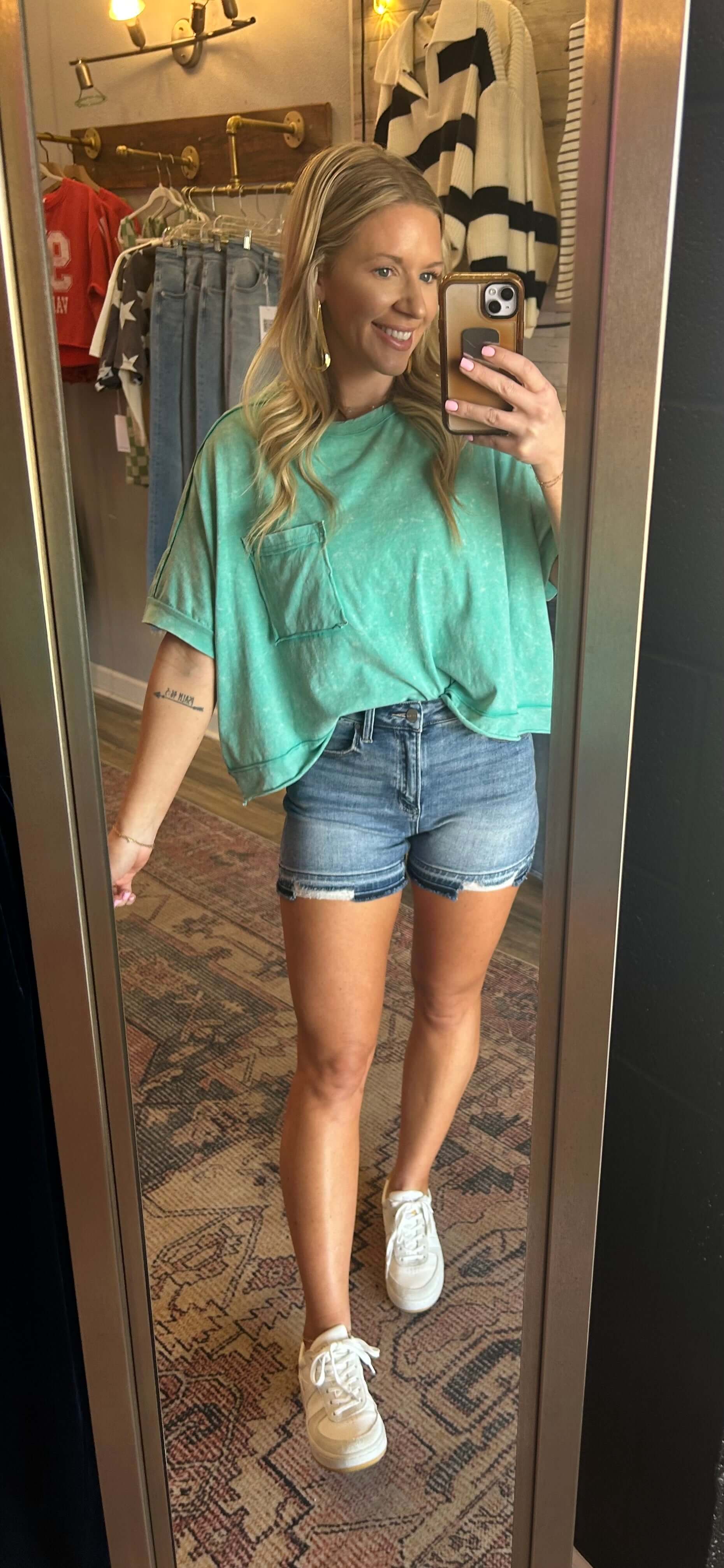 Model wearing a mineral wash crop tee with front pocket detail and distressed shorts in a stylish mirror selfie.