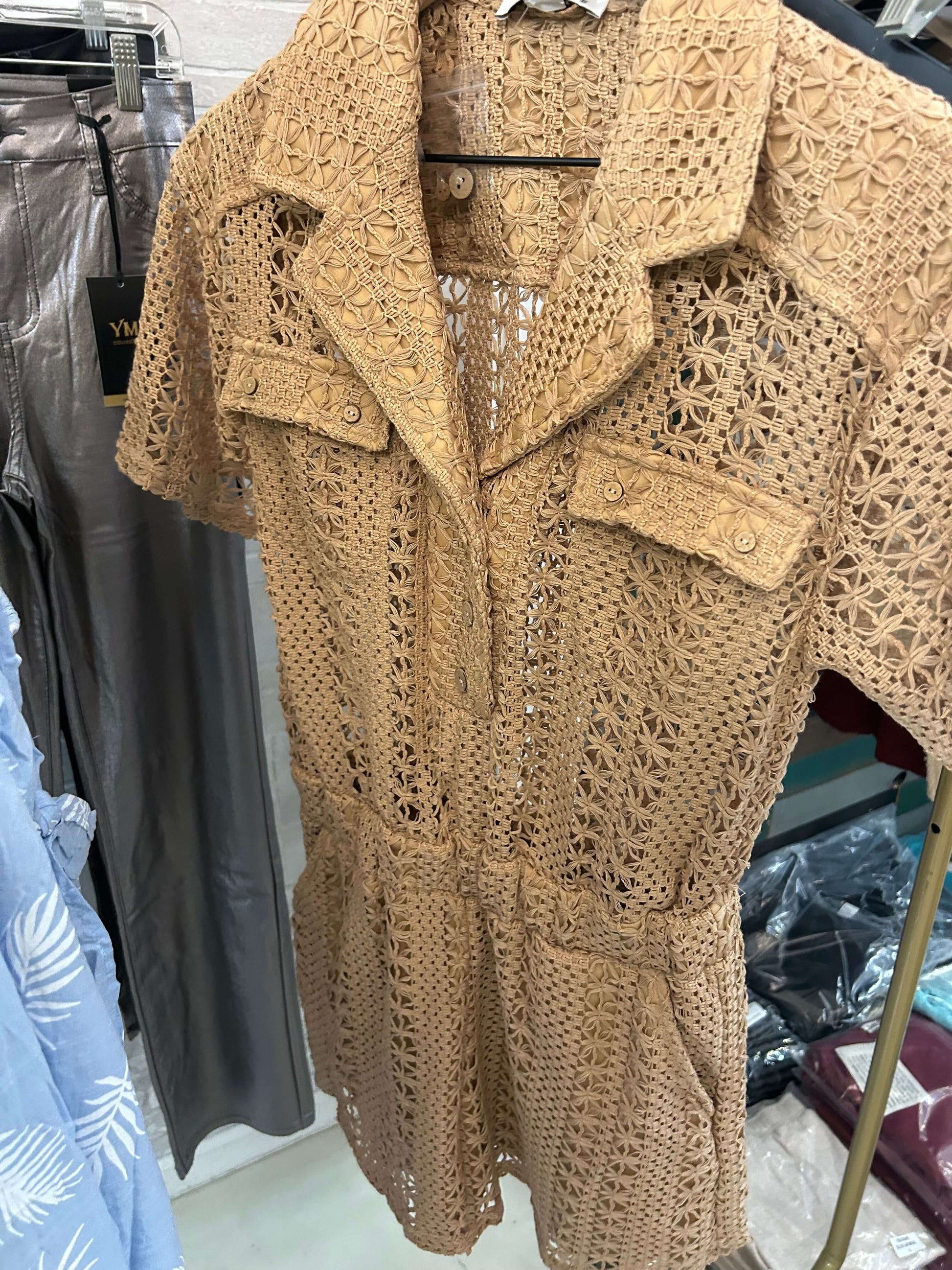 Woven crochet romper in taupe with eyelet details, front buttons, and back pockets for summer style.