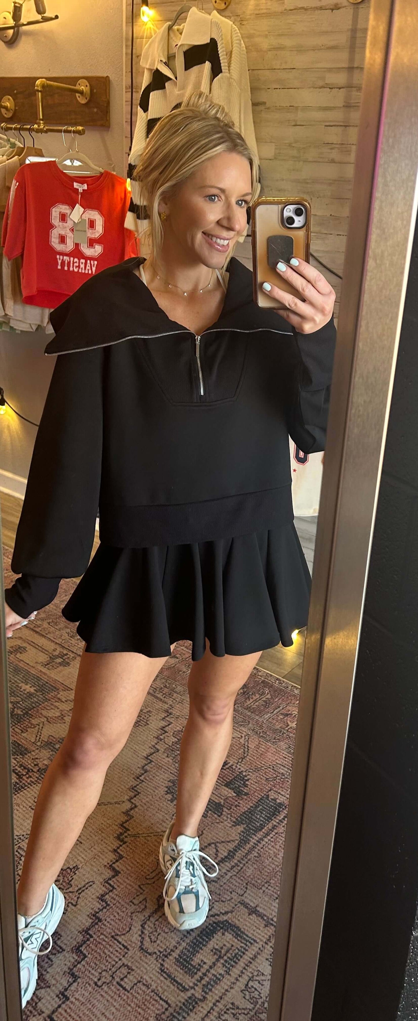 Model showcasing a black neoprene flare skort and pullover set with a cowl turtleneck and built-in shorts.