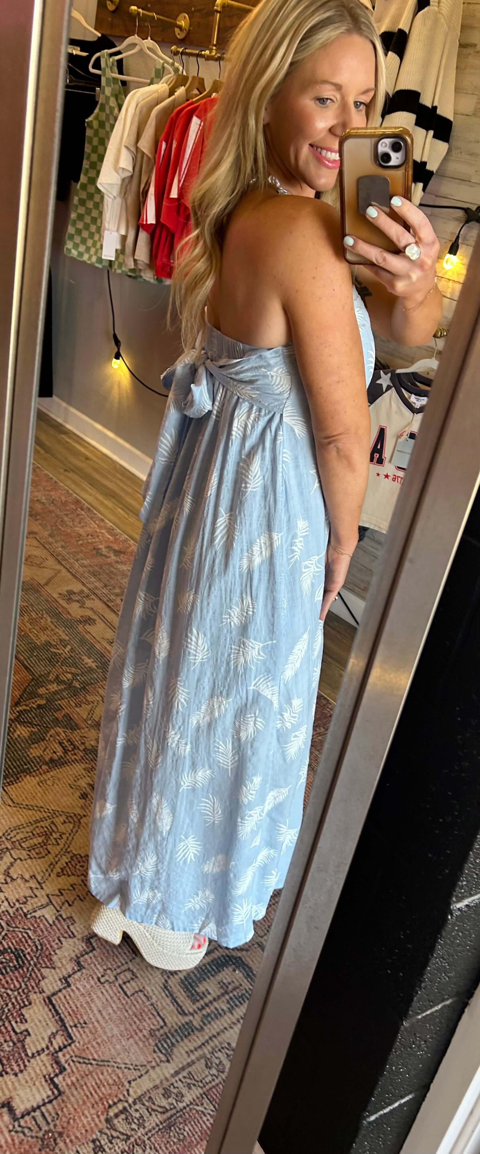 Strapless Summer Breeze Palm Tree Maxi dress with smocked back and bow tie details, displayed by a model in a mirror.