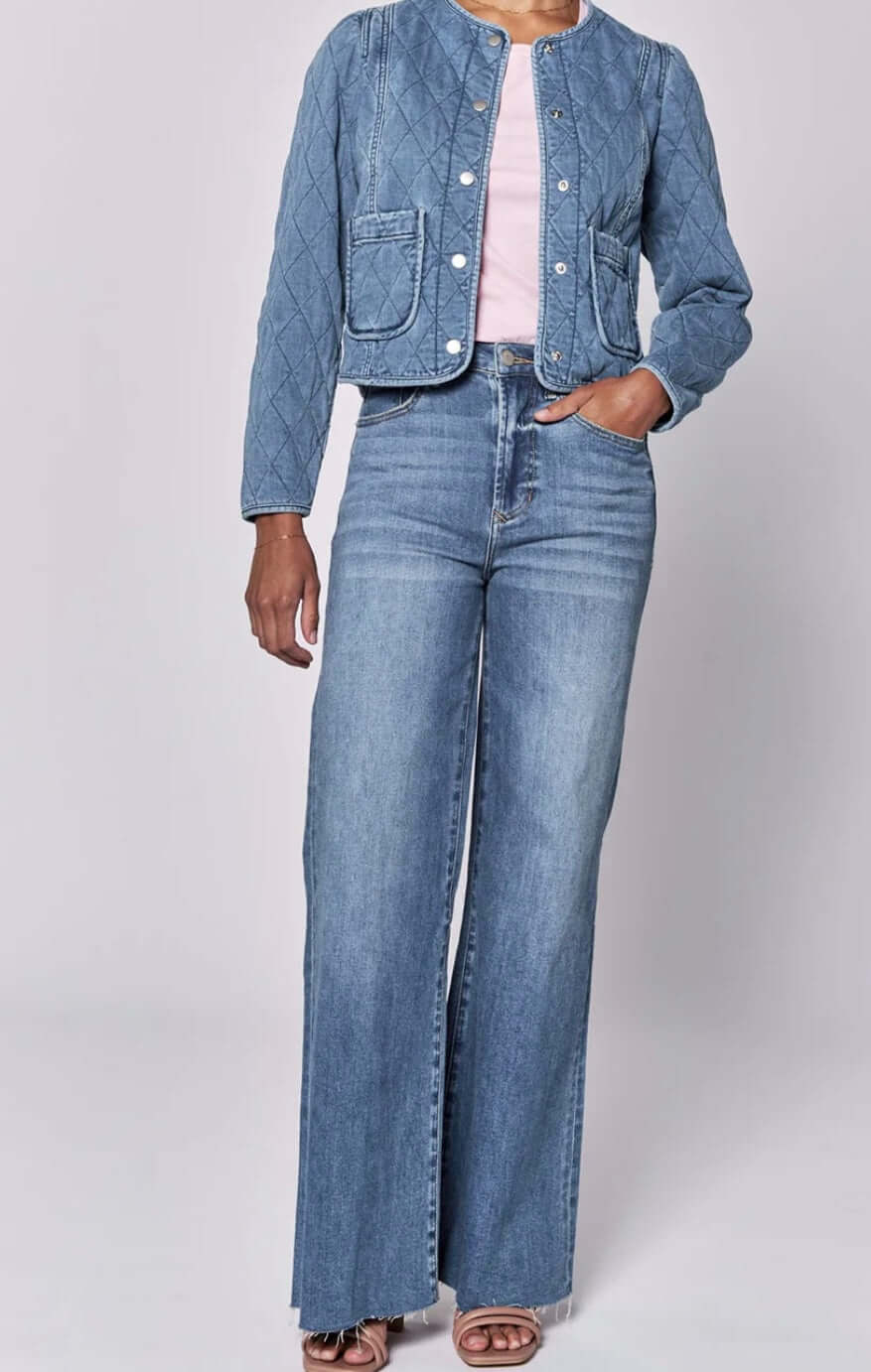 Model wearing a Kit quilted puff sleeve jacket with high-waisted denim jeans and pink top, showcasing trendy style.