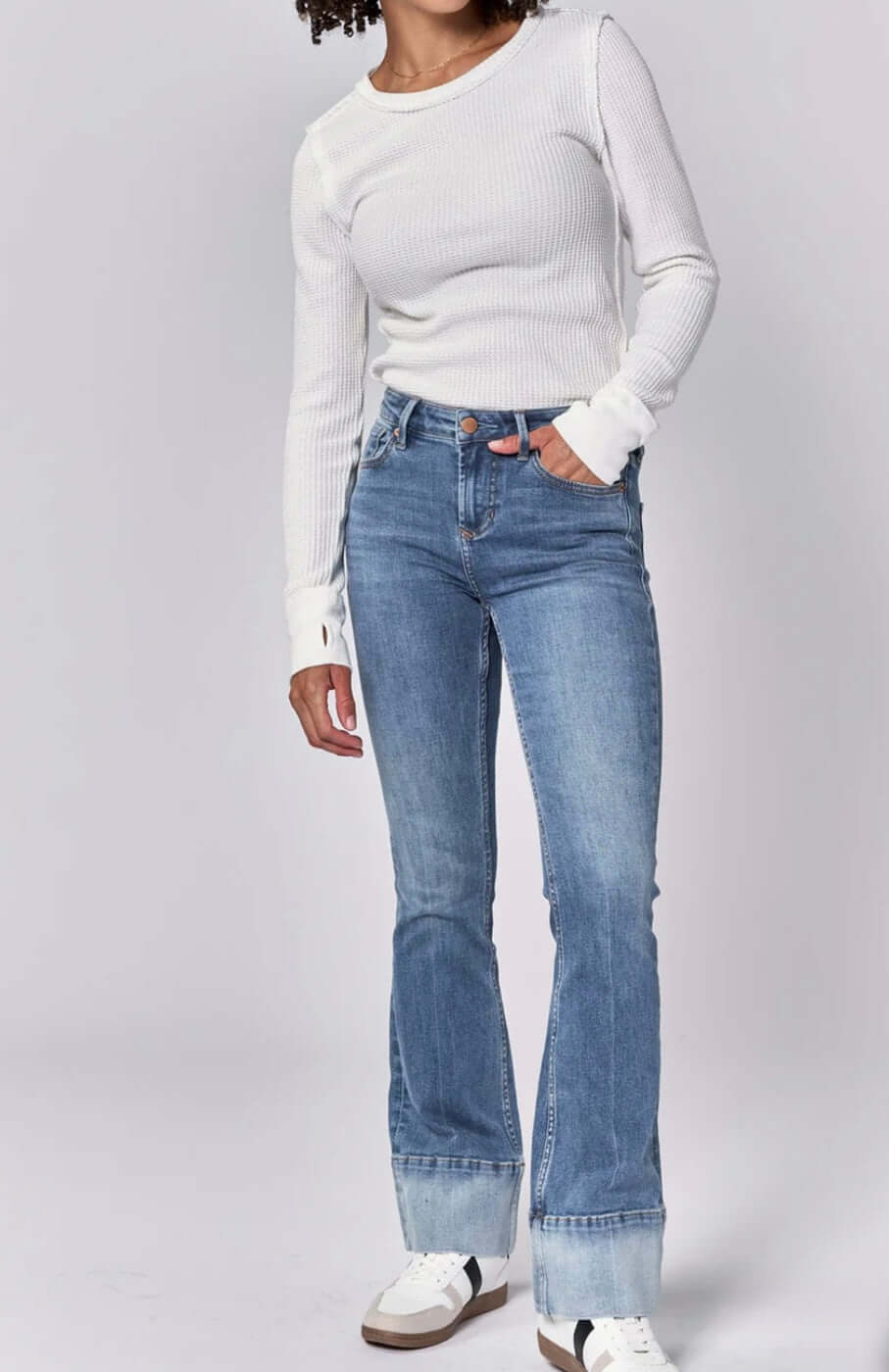 Woman wearing Dear John Jaxtyn mid-rise bootcut jeans in lagoon with a white long-sleeve top.
