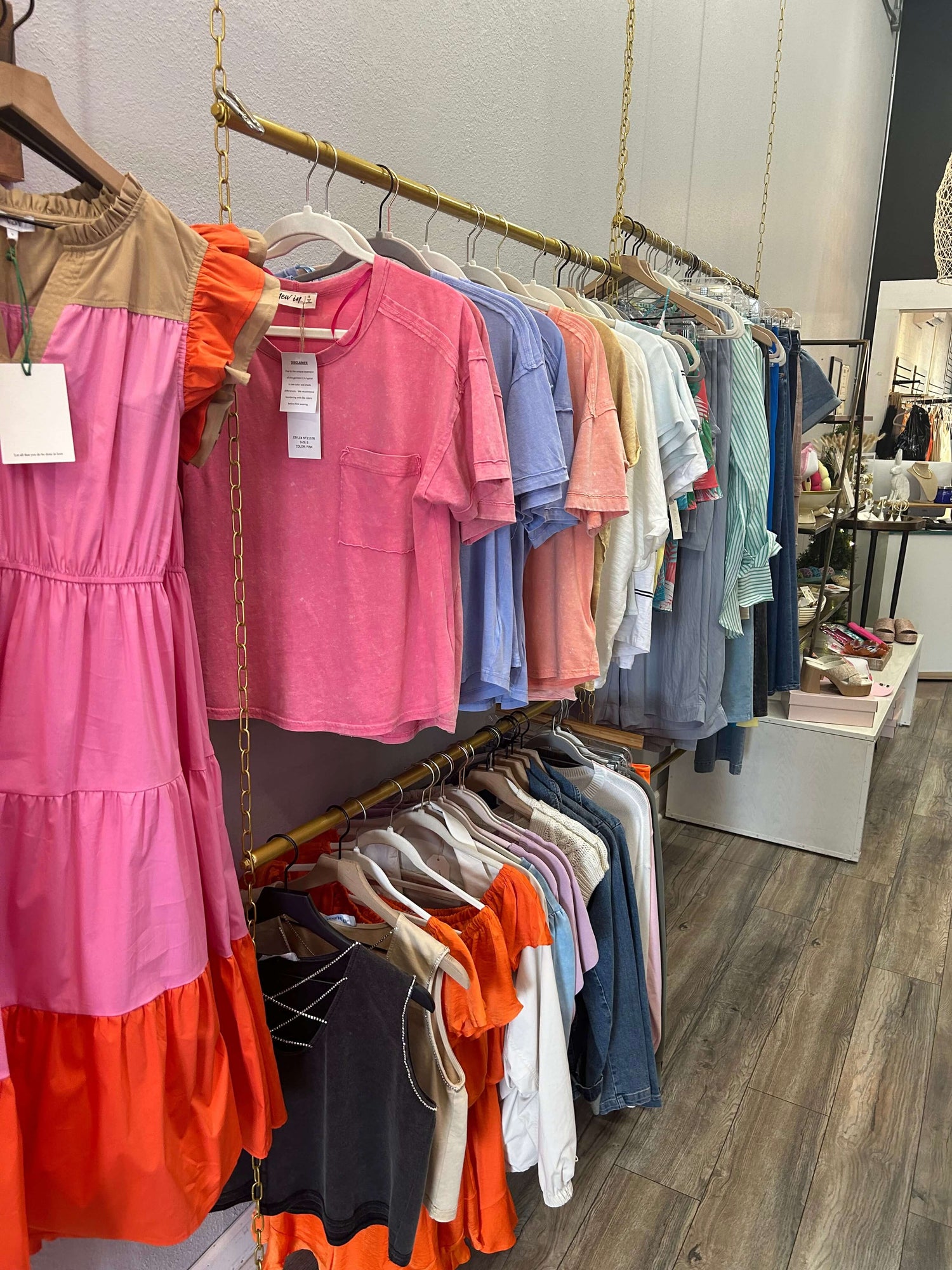 Colorful collection of new women's tops and dresses hanging on display in a stylish boutique.