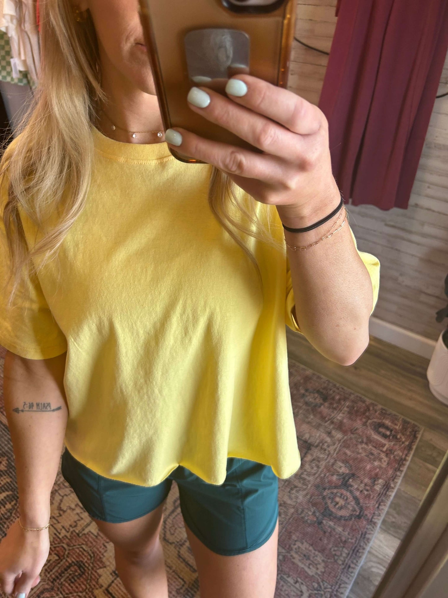 Woman wearing a sunny yellow raw hem tee with green shorts, showcasing a casual summer outfit.