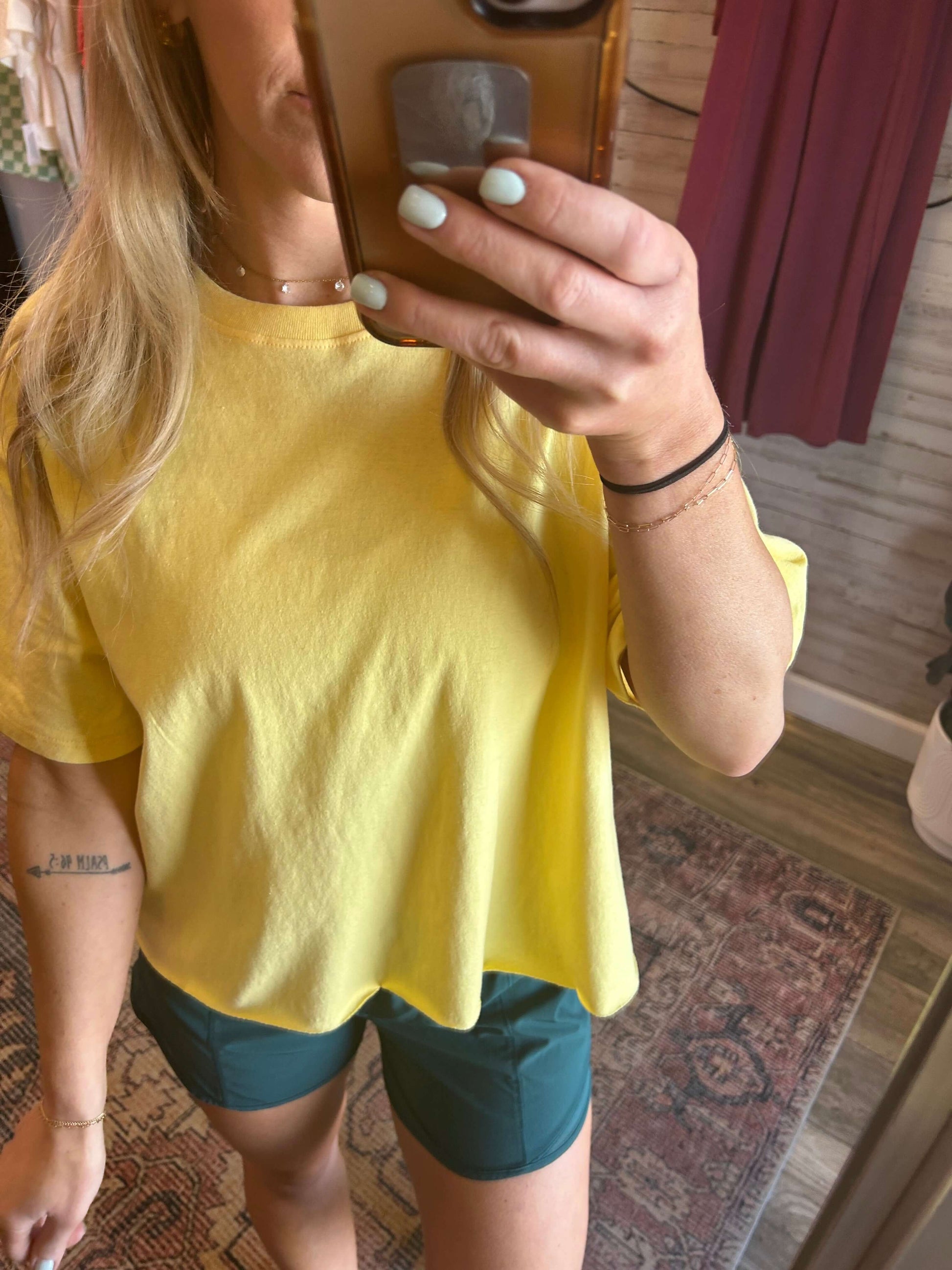 Woman wearing a sunny yellow raw hem tee with green shorts, showcasing a casual summer outfit.